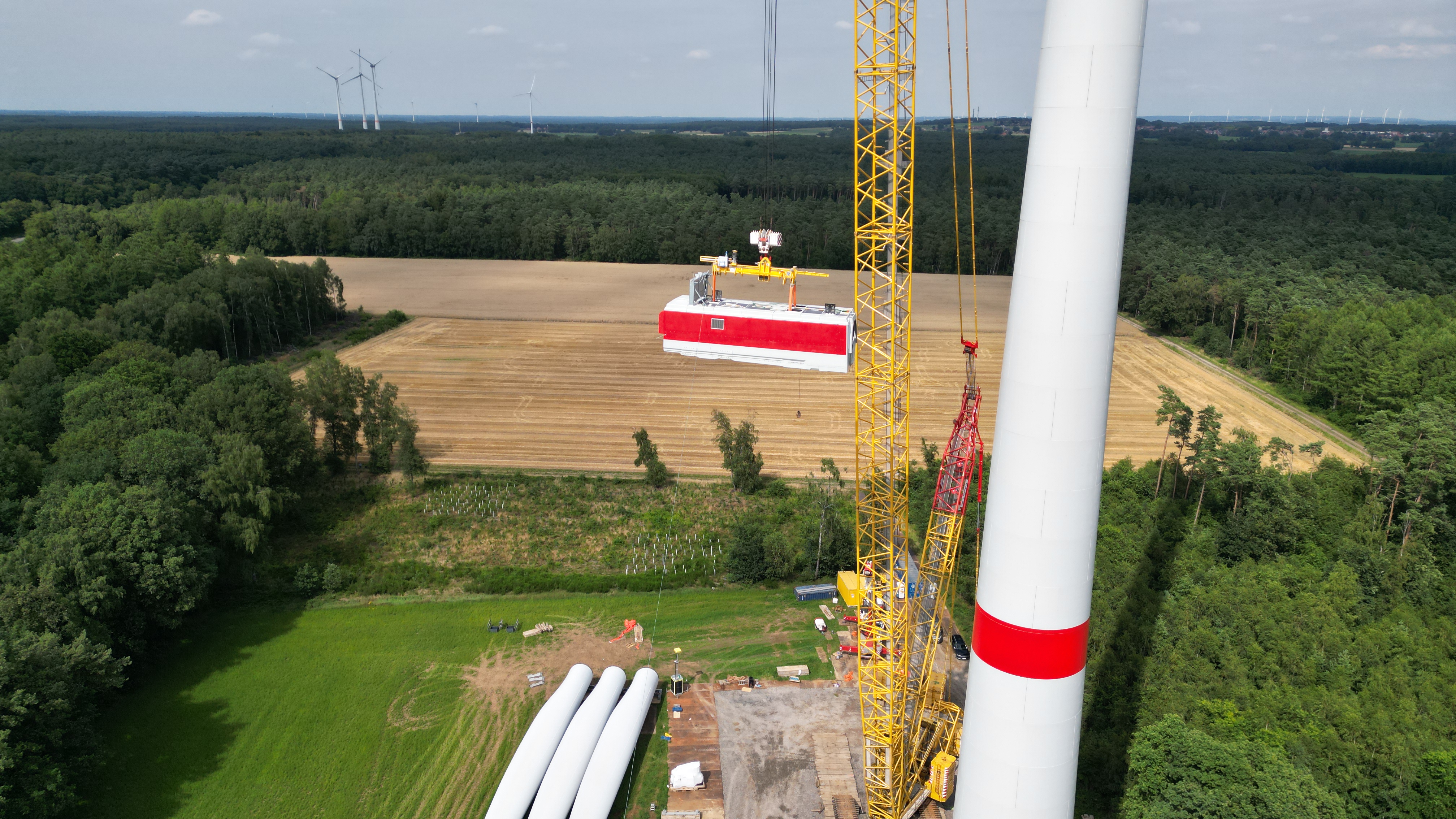 Aufbau einer Windkraftanlage, Gondel wird mit einem Kran nach oben gezogen