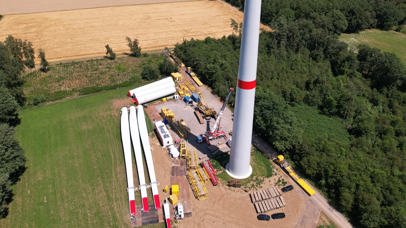Aufbau einer Windkraftanlage, Rotorblätter liegen neben dem Turm, aus der Vogelperspektive gesehen