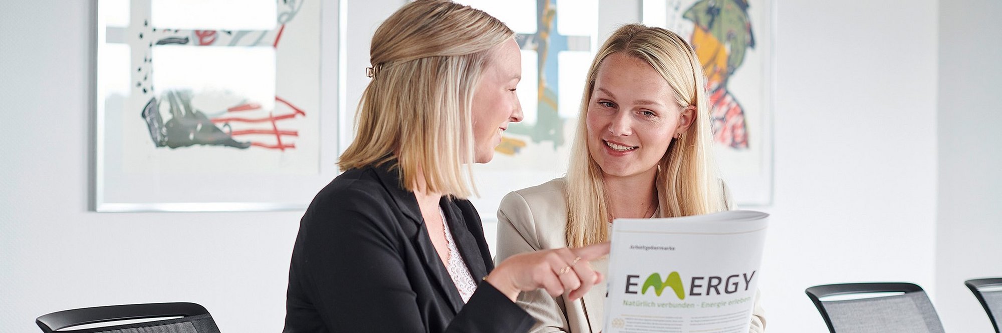 Zwei Frauen sitzen am Tisch und schauen sich eine Broschüre an