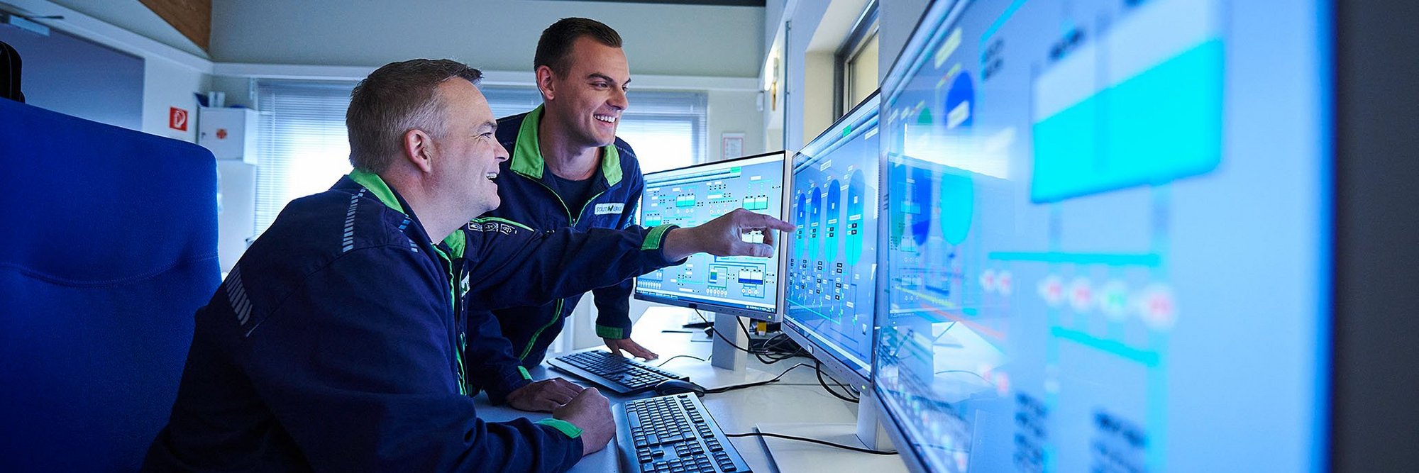 Zwei Techniker in Blaumann vor Monitoren