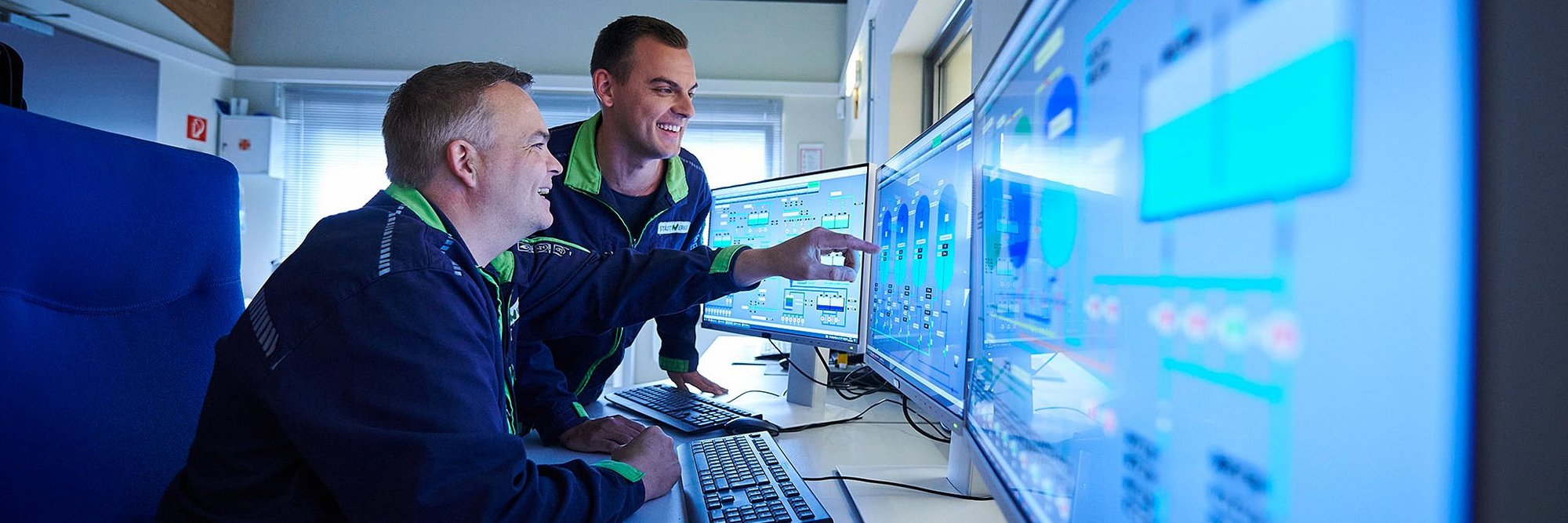 Zwei Techniker in Blaumann vor Monitoren