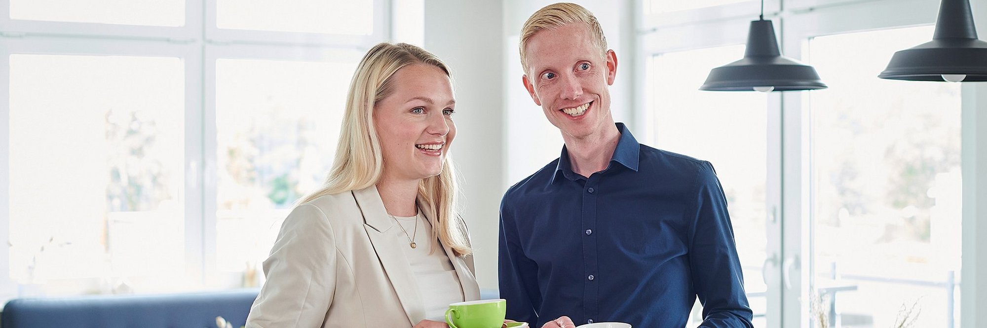 Eine Frau und ein Mann stehen locker am Tisch und trinken Kaffee
