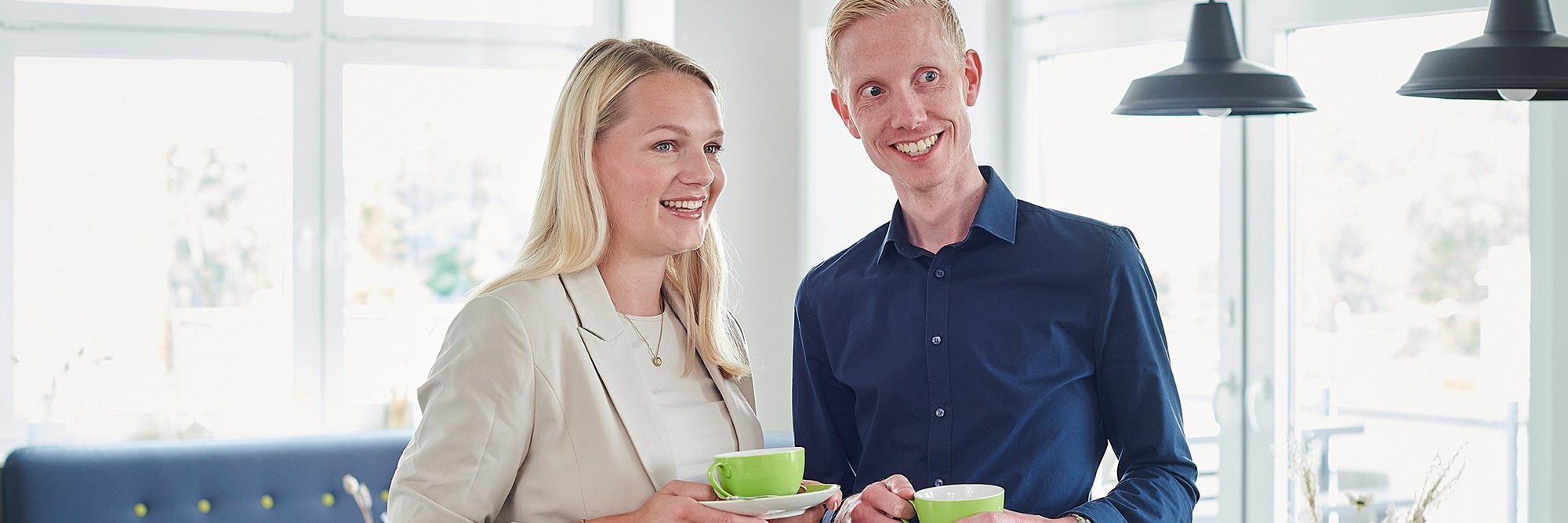 Eine Frau und ein Mann stehen locker am Tisch und trinken Kaffee