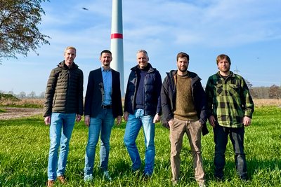 Pressefoto, 5 Männer vor einer Windkraftanlage.