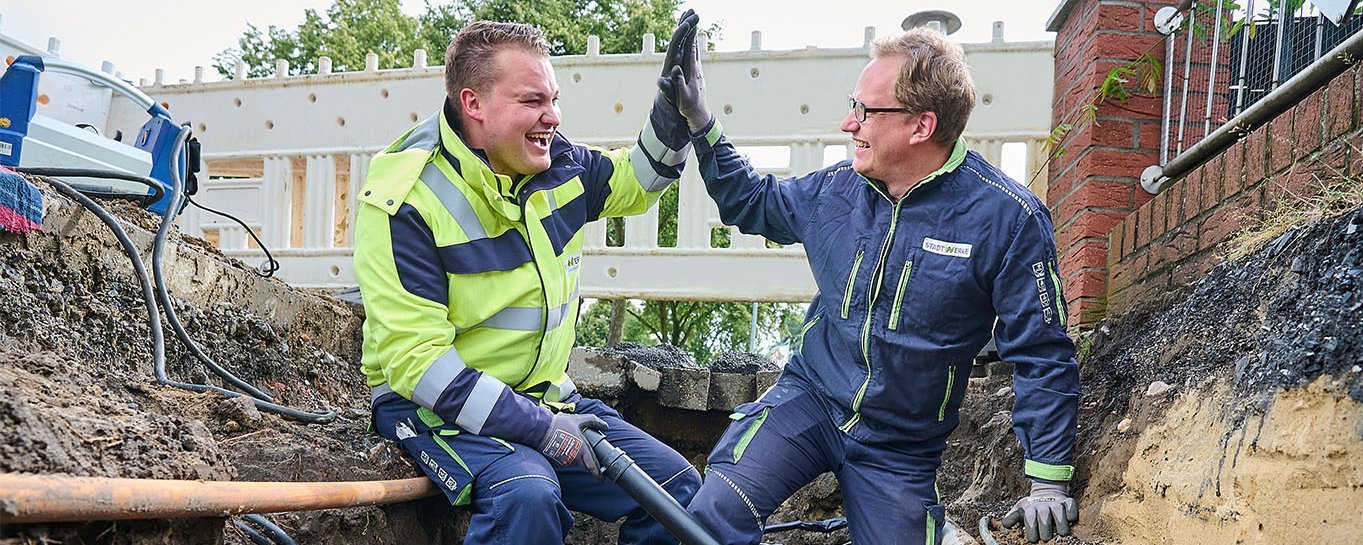 Zwei Techniker sitzen im Leitungsgraben, Rohrleitungen, High Five