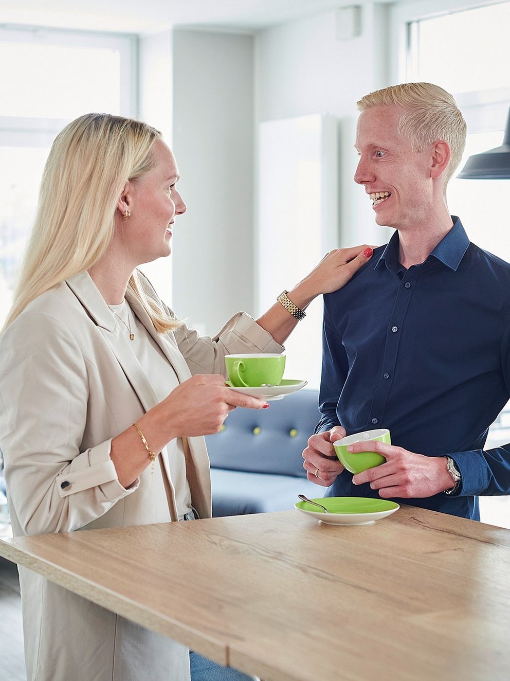 Eine Frau und ein Mann stehen locker am Tisch und trinken Kaffee