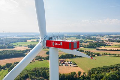 Das Bild zeigt eine Windkraftanlage (WKA) aus der Drohnenperspektive. Auf der Gondel steht das Logo der Emergy.